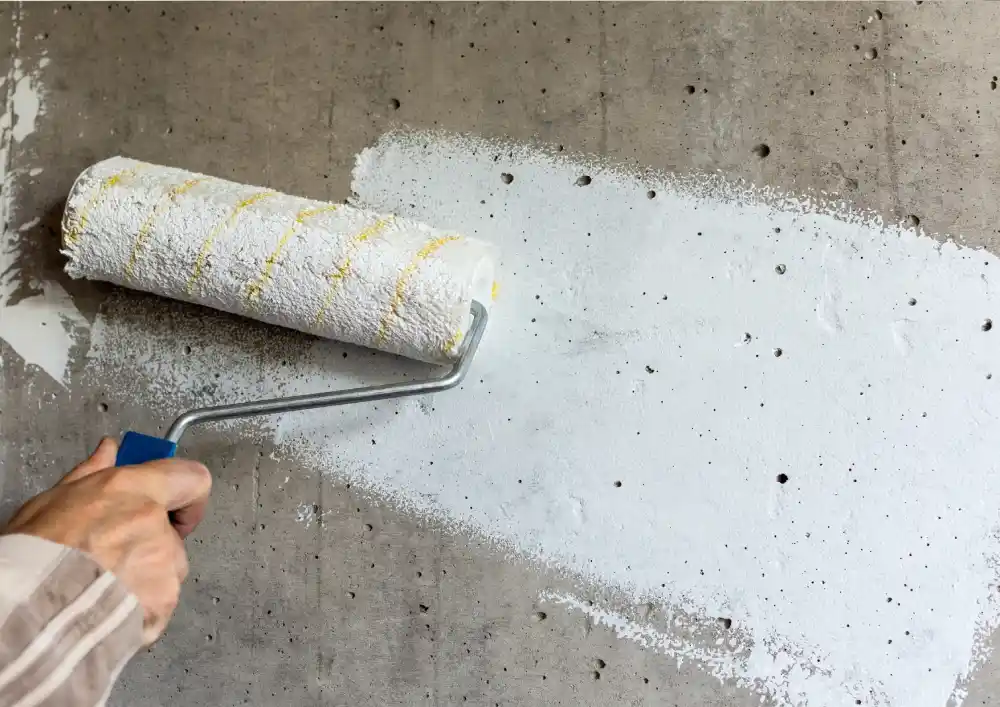 Professional painting of a concrete floor in a garage using grey epoxy paint.