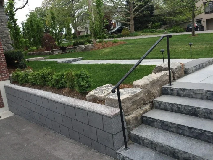 A rebuilt concrete retaining wall with steps and landscaping