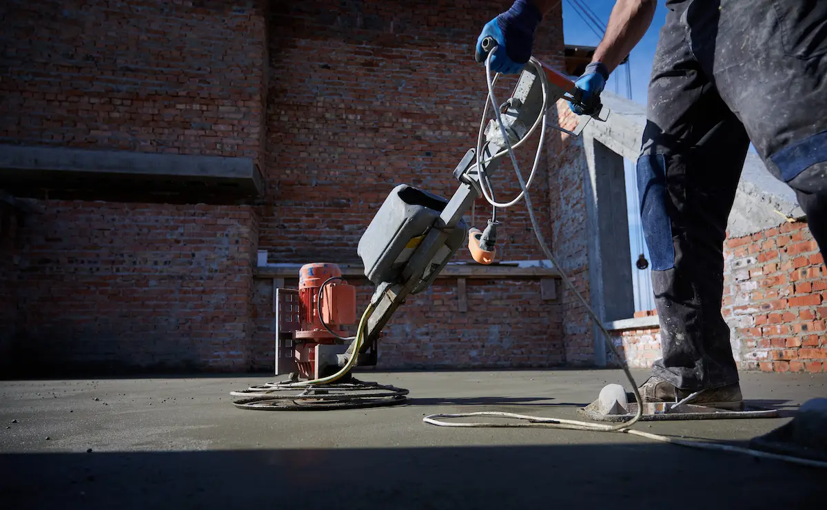 A person filling cracks in an concrete with a specialized crack filler tool.